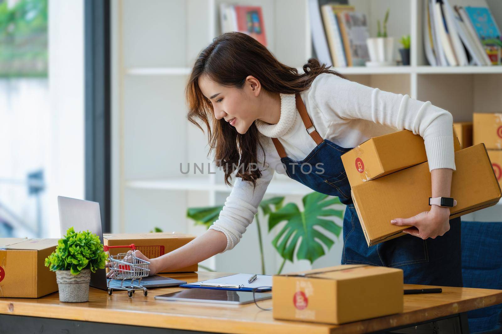 Work from home. happy women selling products online Start a small business owner by using laptop computer to calculate prices and prepare for postage