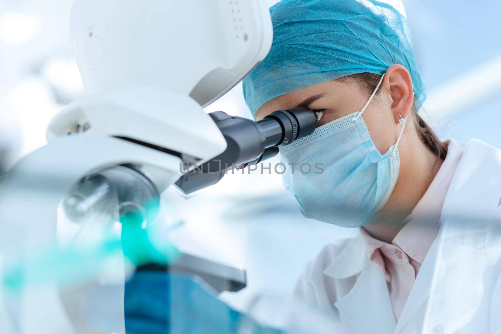 close up. female scientist looking carefully through a microscope. science and health protection.