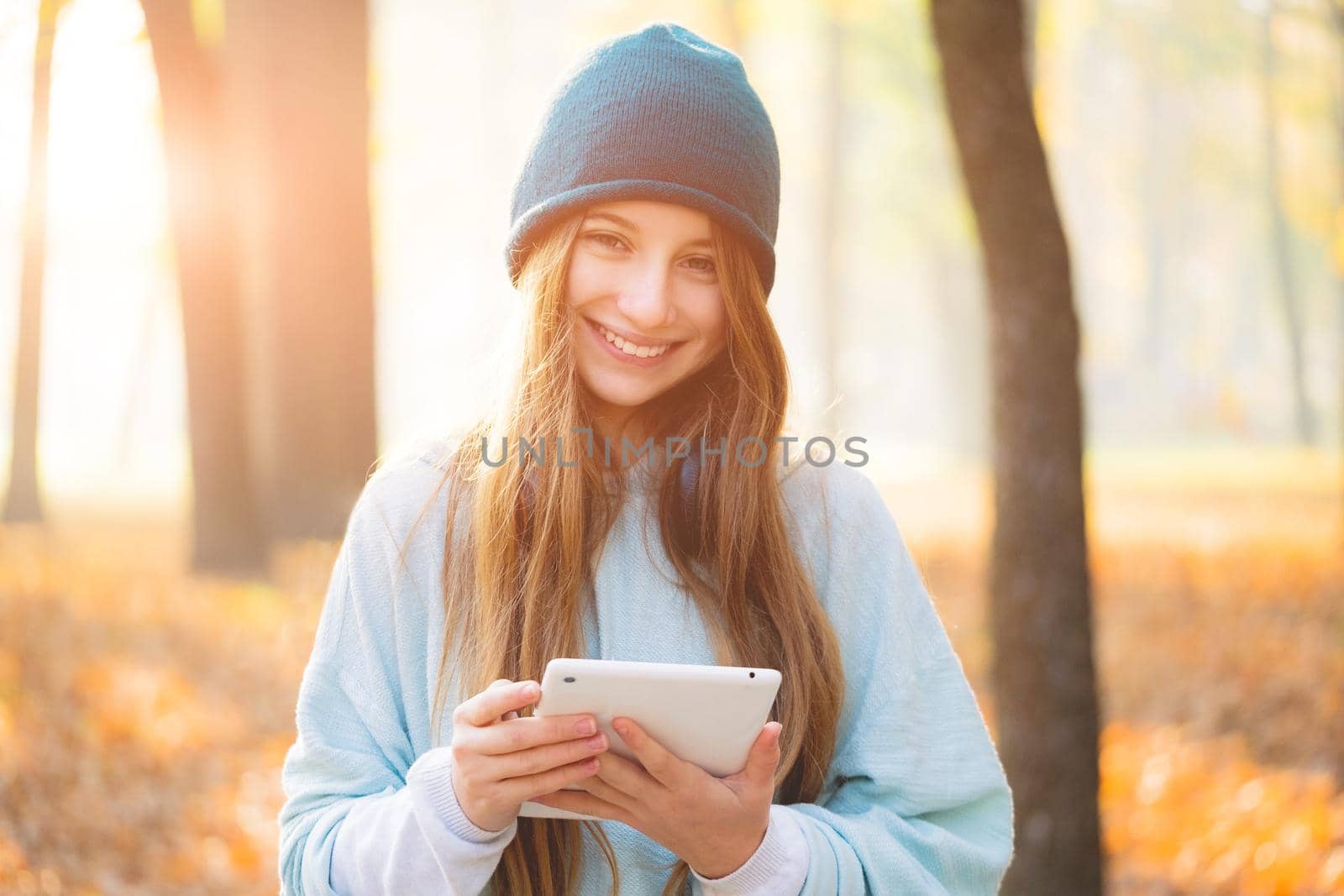 Cute girl with tablet in autumnal park