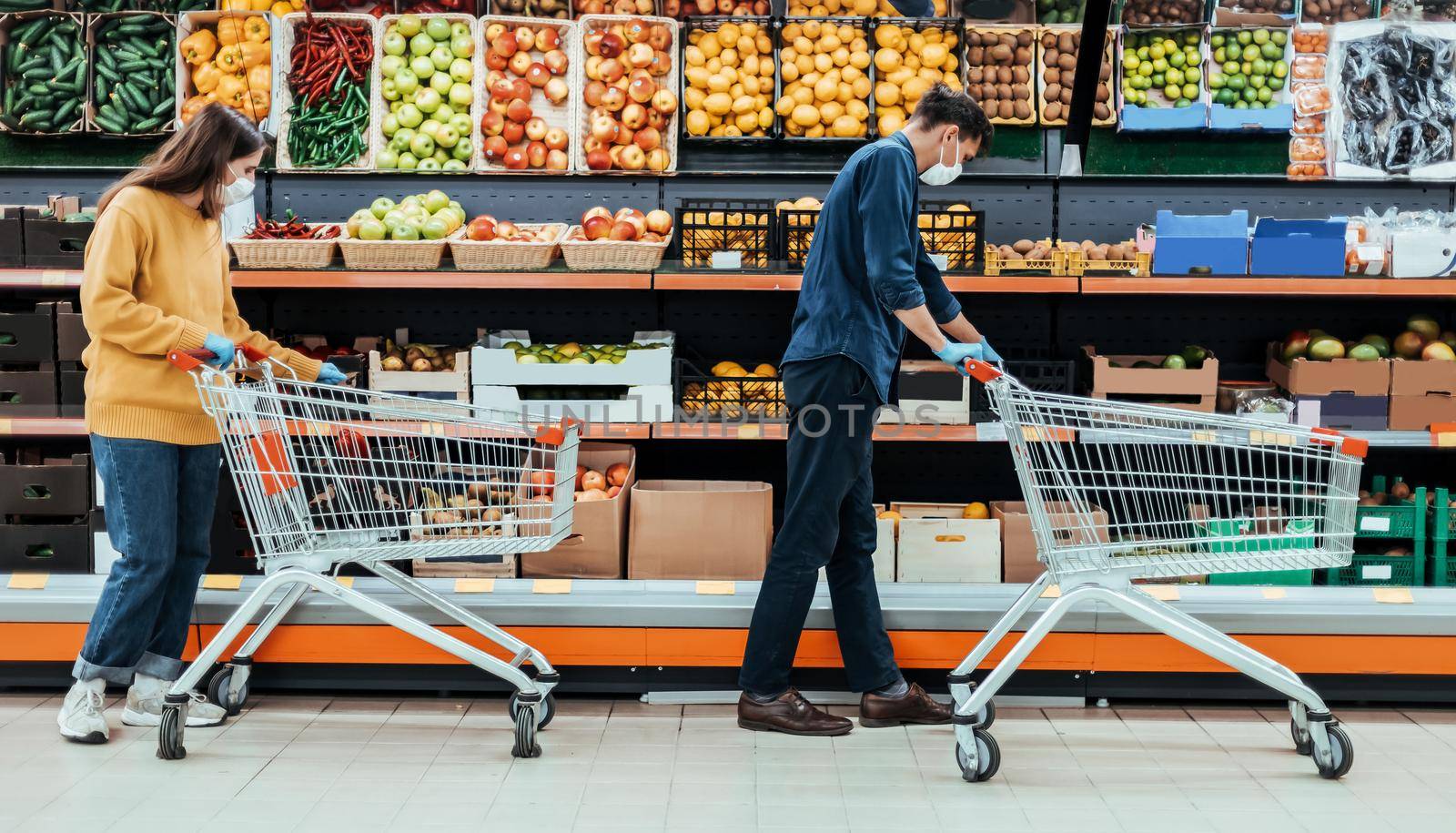 man and a woman with shopping carts in a supermarket during the quarantine period. photo with a copy-space