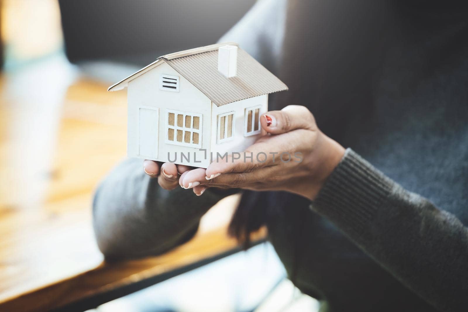 Female hand holding a house model, insurance concept and home loan. by Manastrong