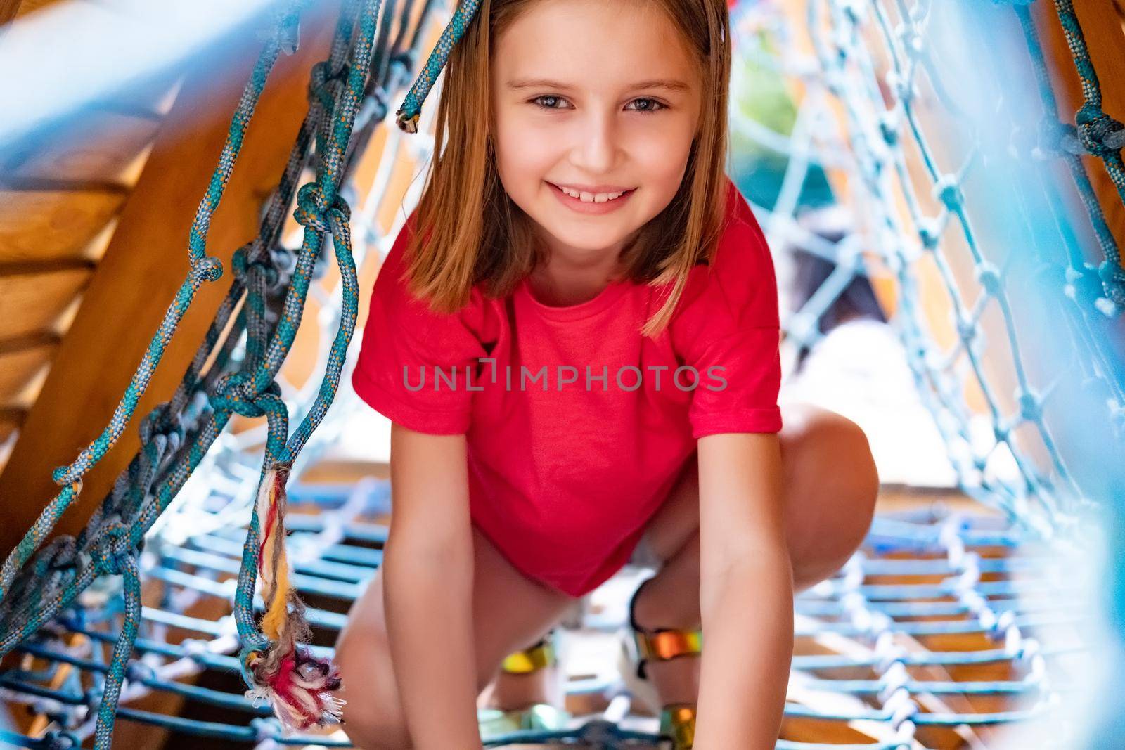 Little girl playing on climbing net on park playground