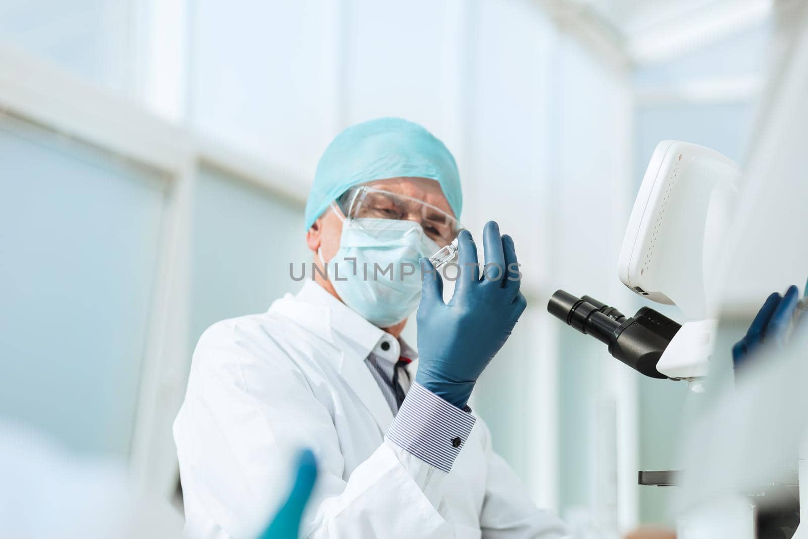 close up. scientist in with an ampoule sitting at a laboratory table . photo with a copy-space.