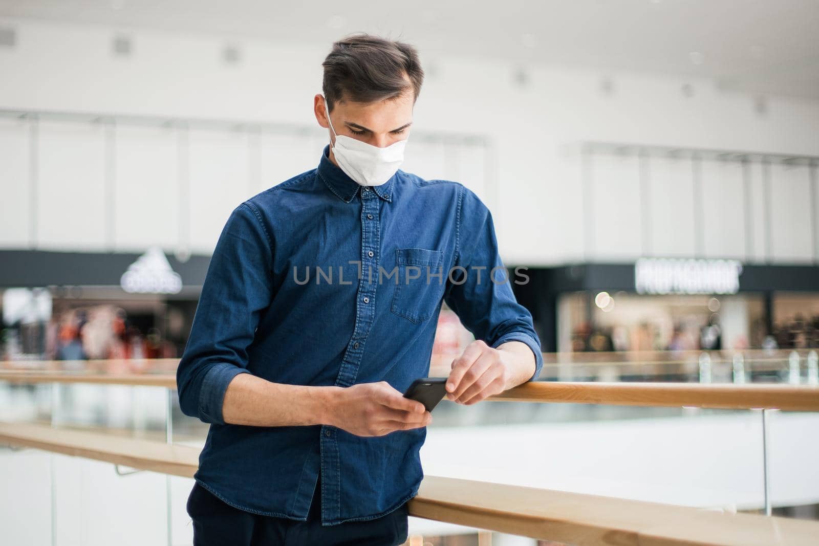 man in a protective mask with a smartphone standing on the street . photo with a copy of the space