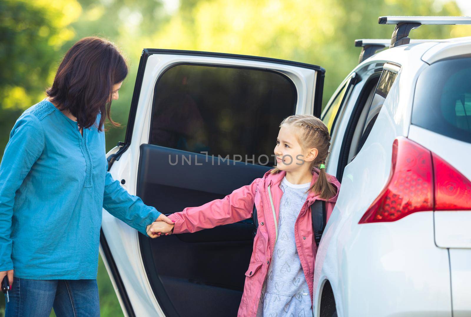 Mother with school girl sitting in car after classes