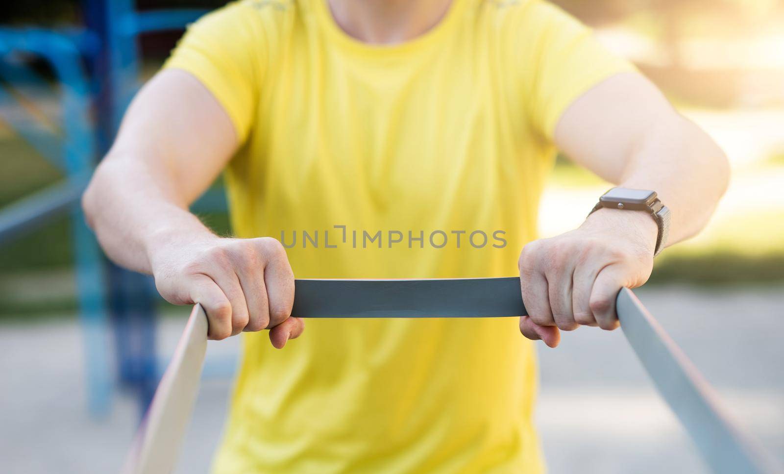 Man stretching with elastic rubber during street workout