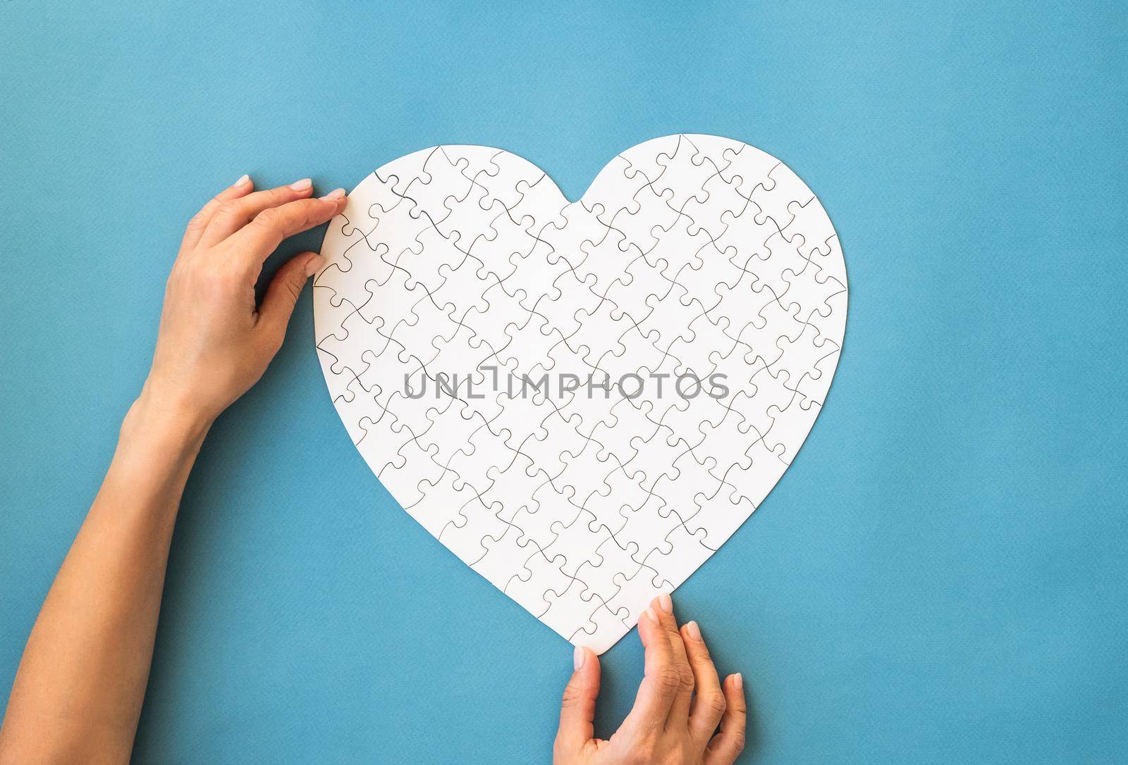 White puzzle in heart shape on a blue background