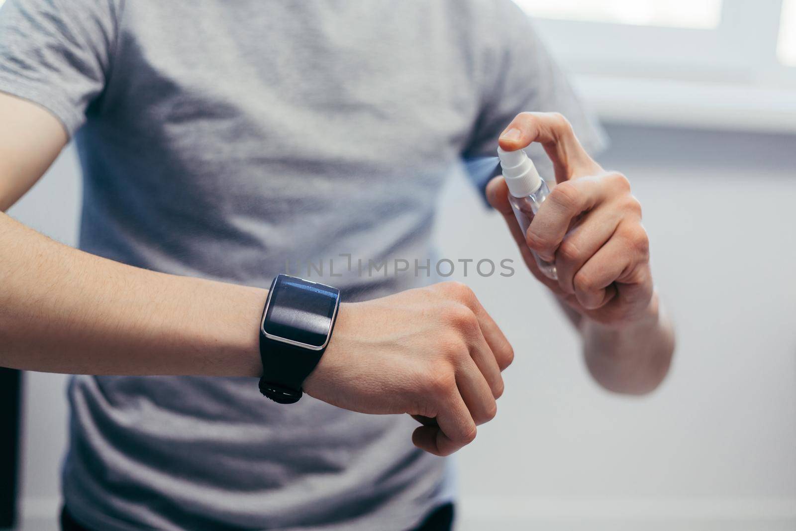 close up. casual man spraying disinfecting his smart watch.