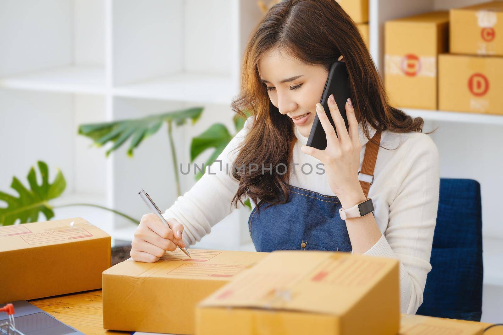 Work from home. happy women selling products online Start a small business owner by using smartphone and laptop computer to calculate prices and prepare for postage