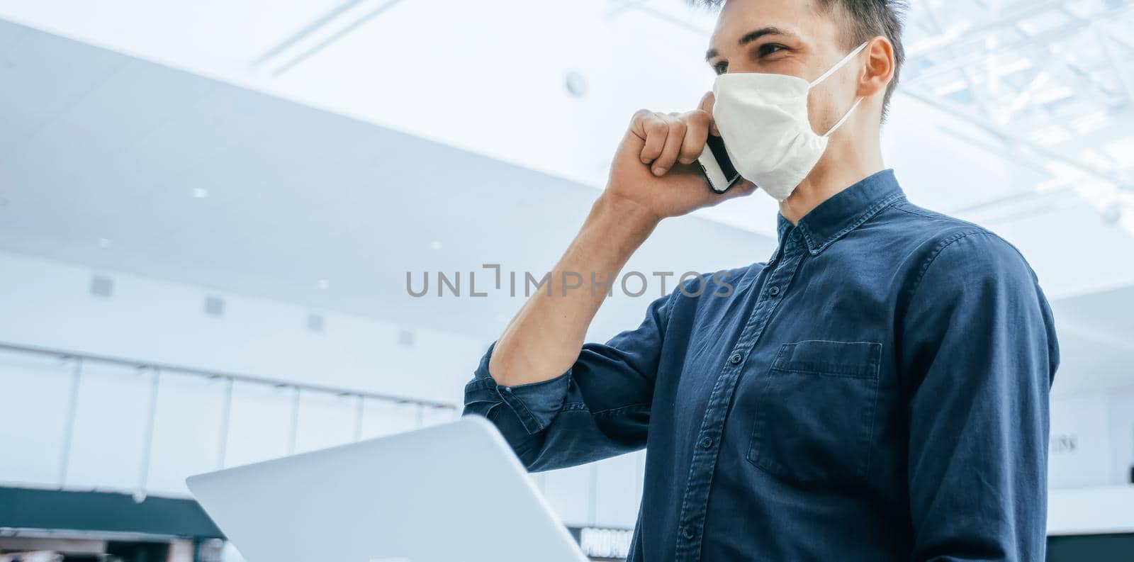 young man in a protective mask talking on a smartphone. by SmartPhotoLab