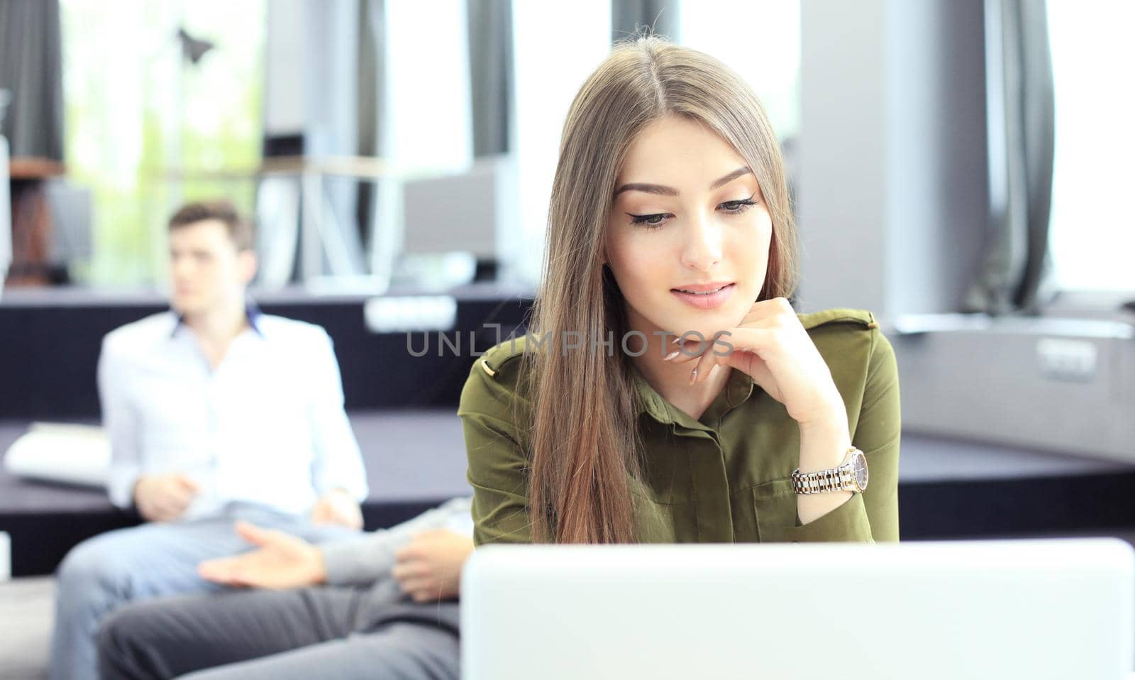 young woman smiling and typing on laptop in modern office.