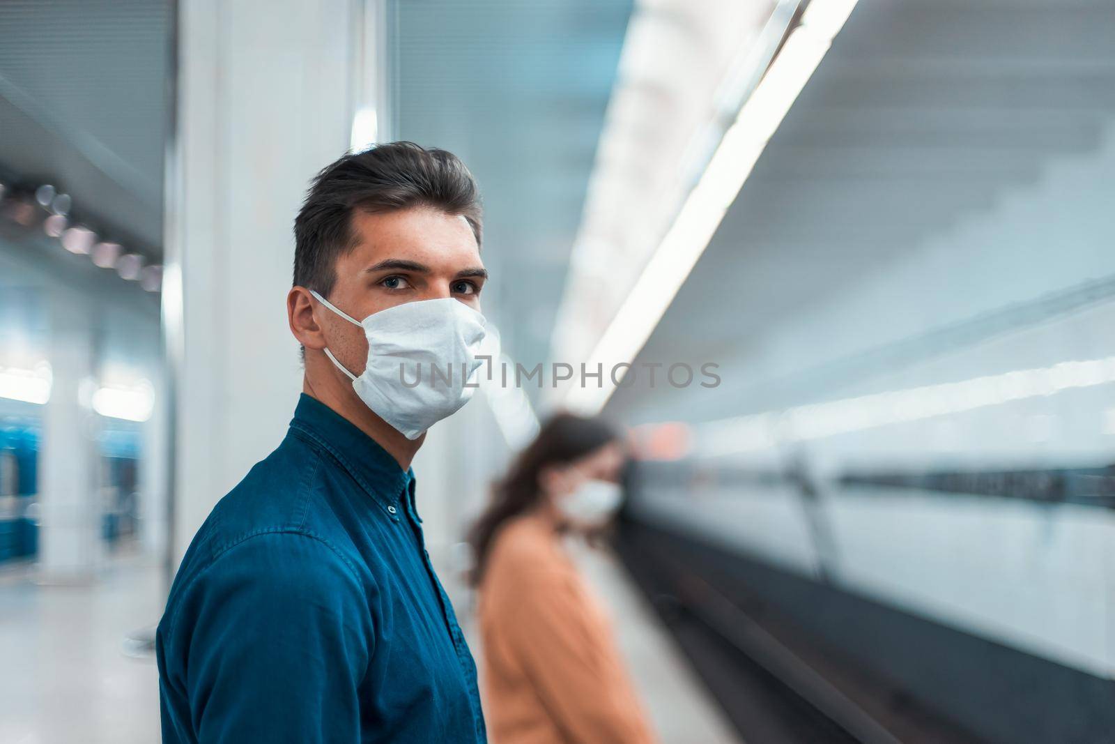 passengers in protective masks standing at a metro station at a safe distance . coronavirus in the city