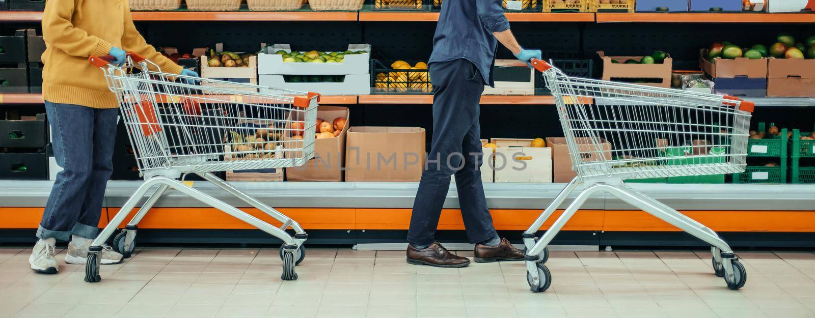 man and a woman with shopping carts in a supermarket during the quarantine period. photo with a copy-space