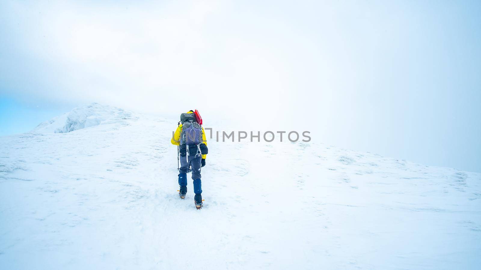 Lonely tourist trekking winter mountain top covered with snow