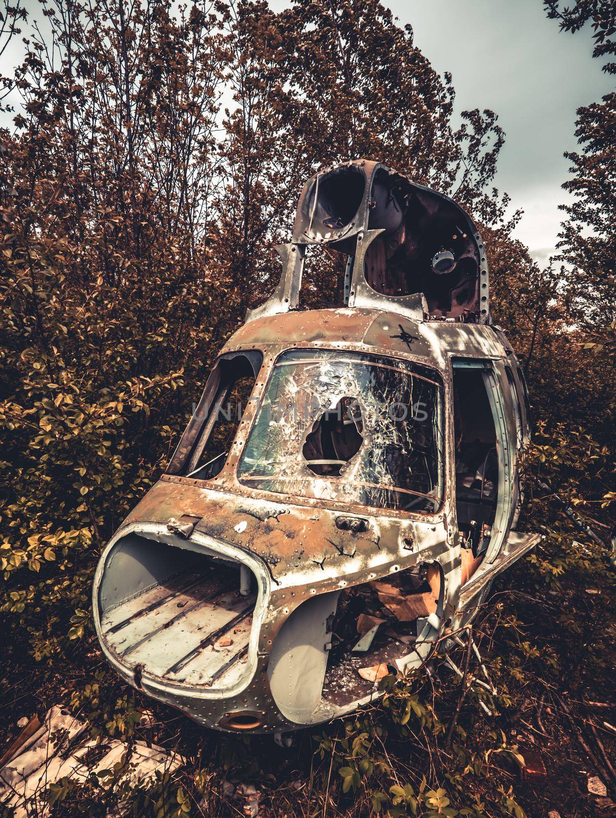 Abandoned destroyed cabin of old USSR helicopter with broken glass in the wild nature closeup