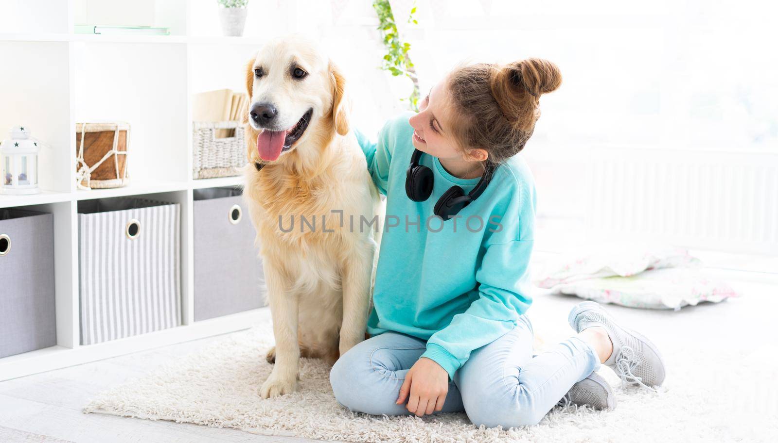 Happy girl with lovely golden retriever dog in bright room