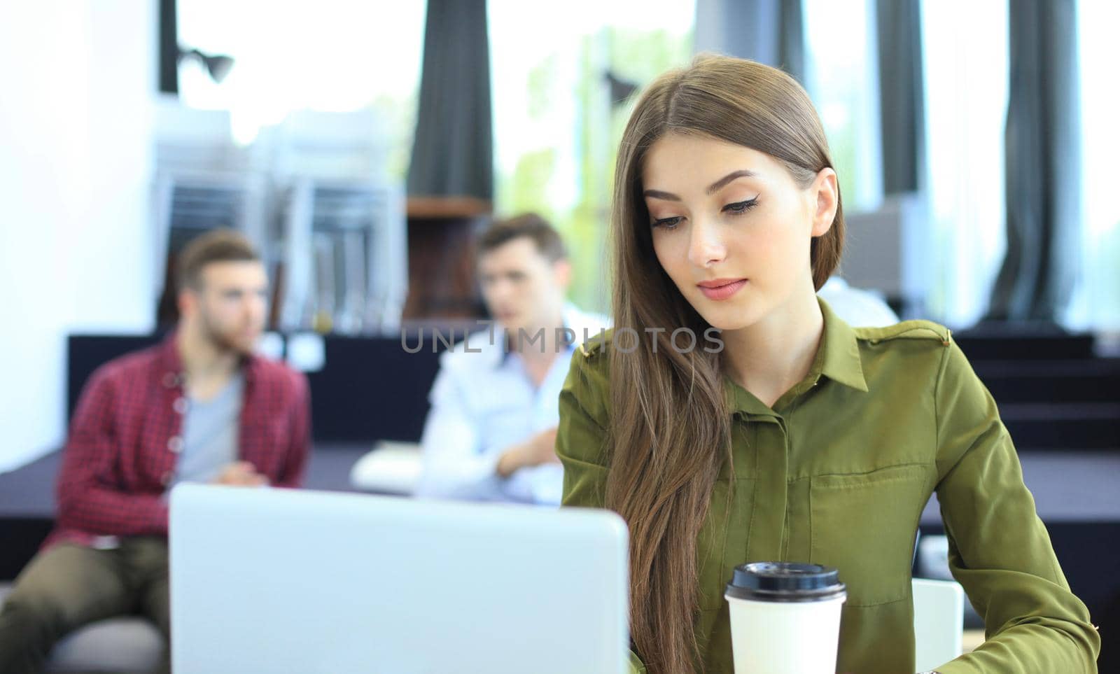 young woman smiling and typing on laptop in modern office.