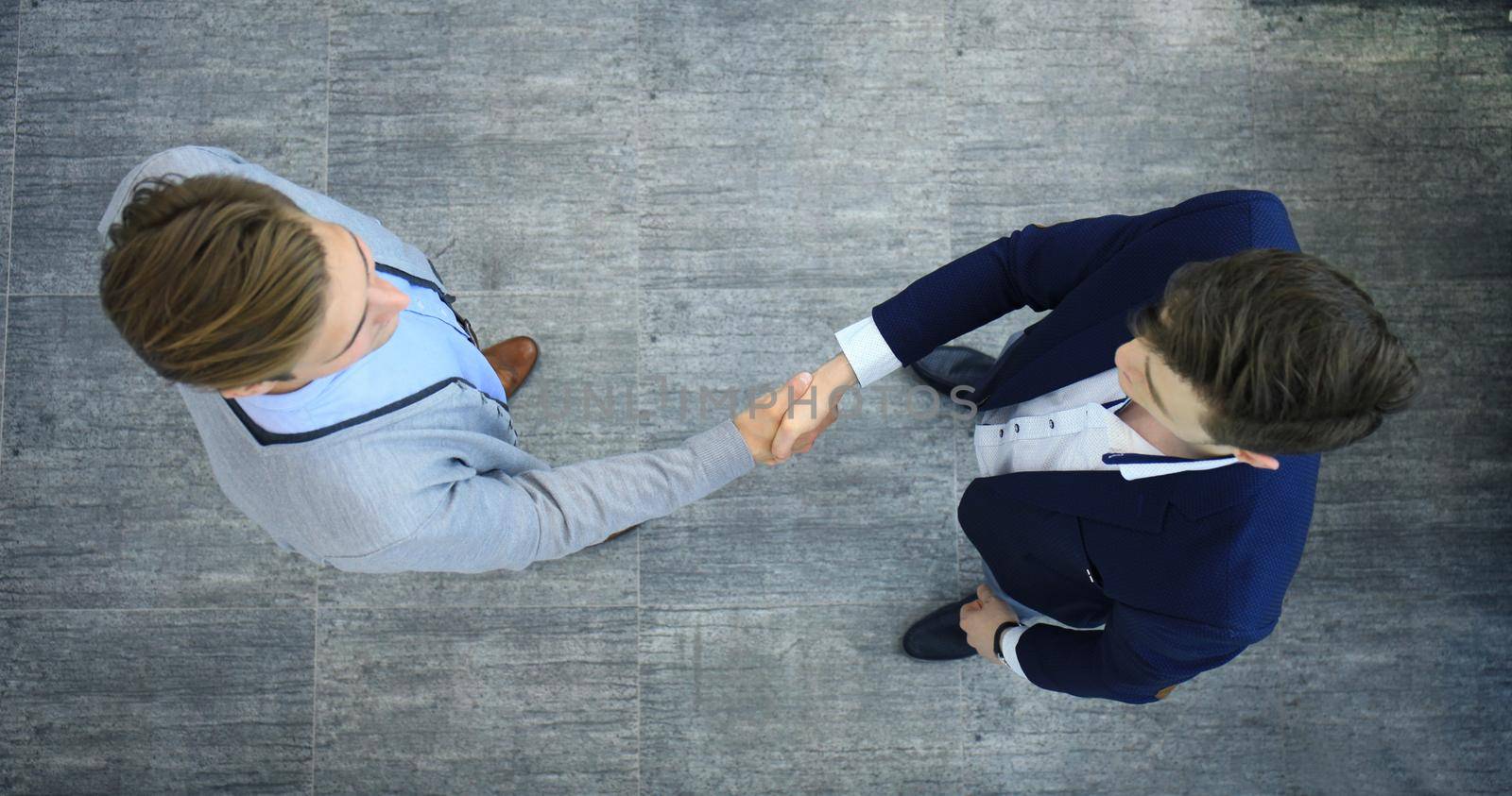 Top view of a two businessman shaking hands. Welcome to business. by tsyhun