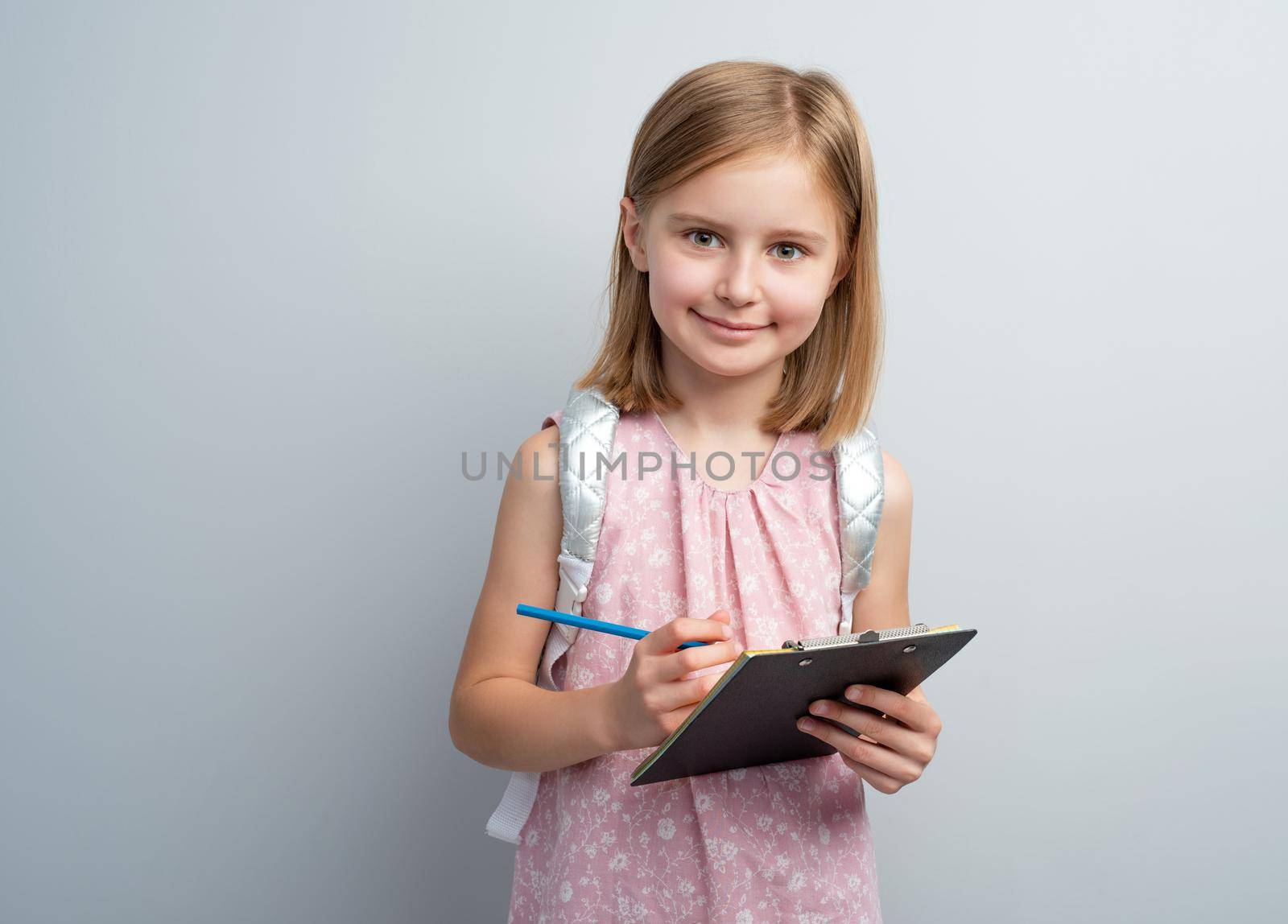 Schoolgirl with pencil taking notes in writing pad indoors