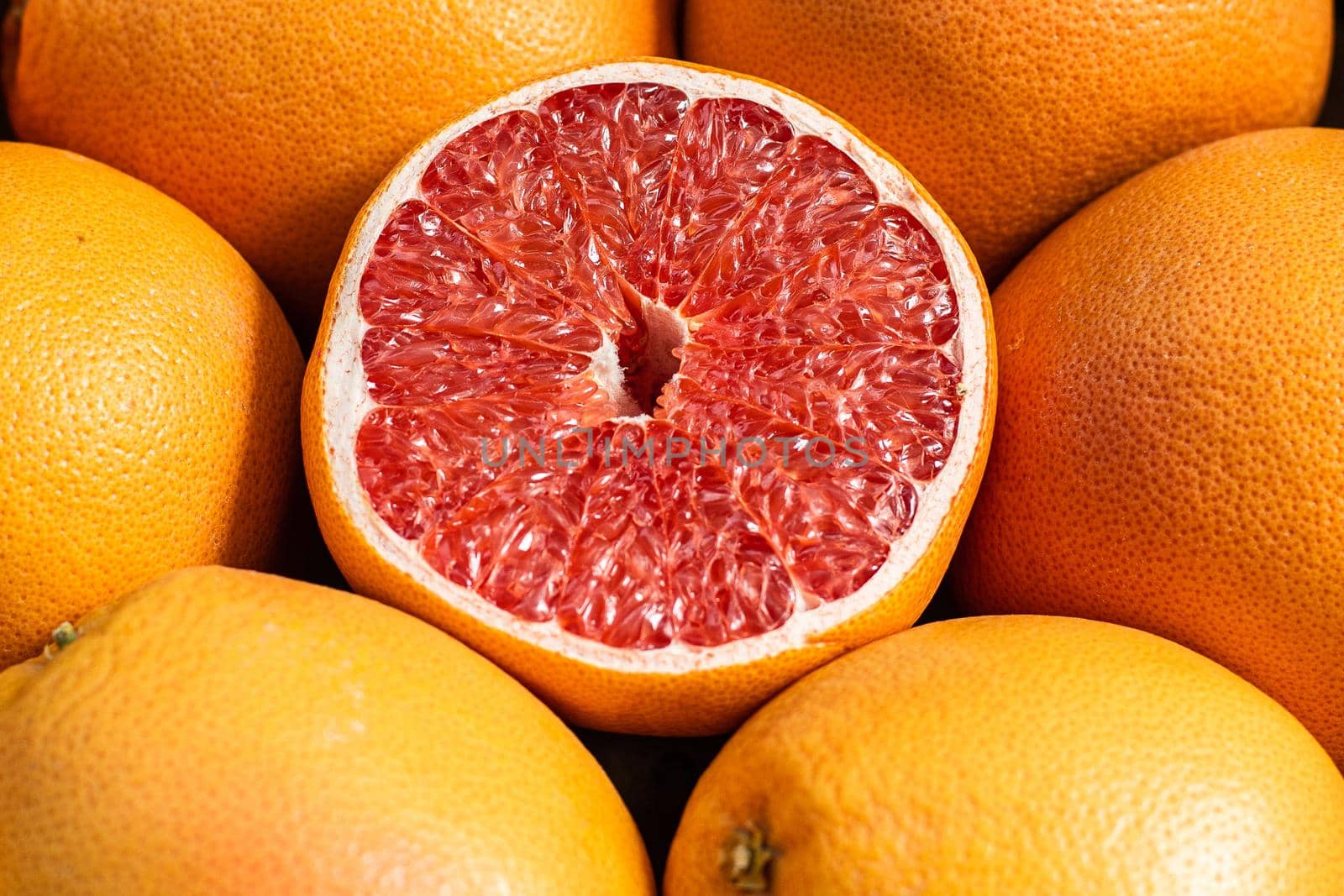 Close up of juicy halved orange lying near delicious fresh oranges at a fruit stall. Ripe fruit background