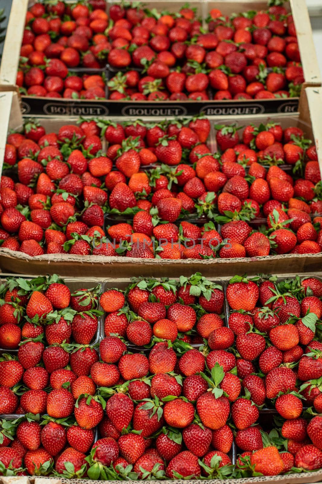 Picture of sweet, tasty and fresh strawberries lying in wooden boxes in the store by StudioLucky