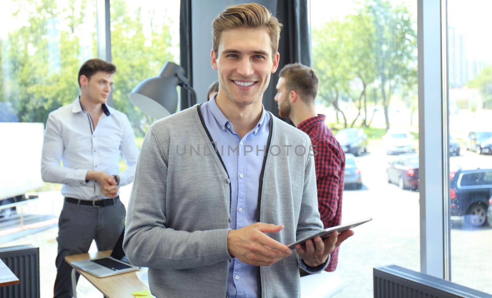 Smiling young man using digital tablet in the office. by tsyhun