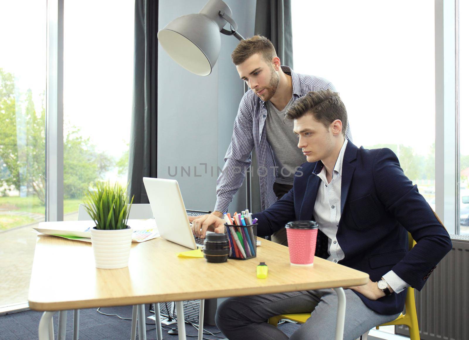 Two young modern men discussing work in the office studio.