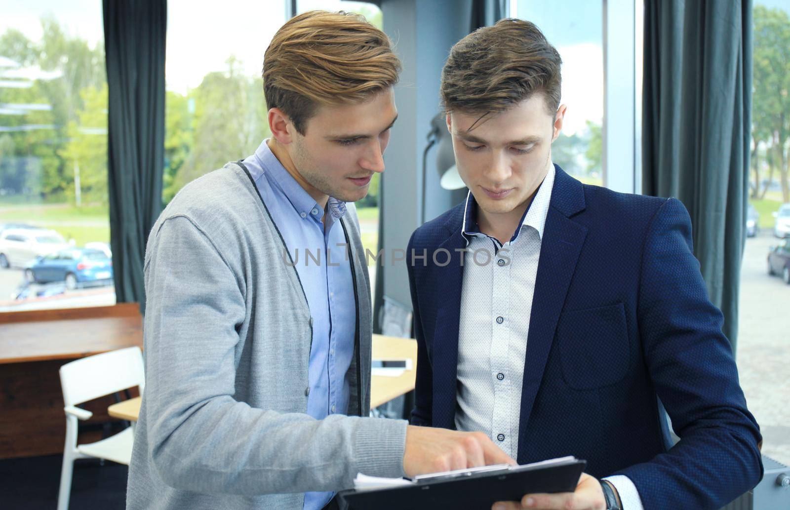 Two young modern men discussing work in the office. by tsyhun