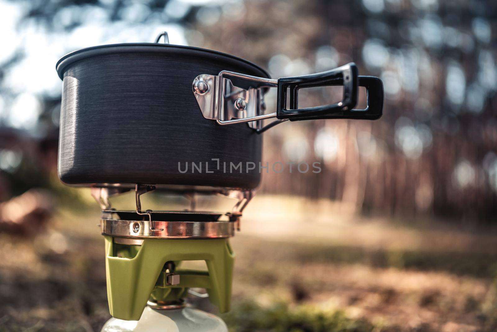 Cooking process in the camping in the wood with pan and gas burner equipment for food preparation. Picnic at the nature in the forest for travellers