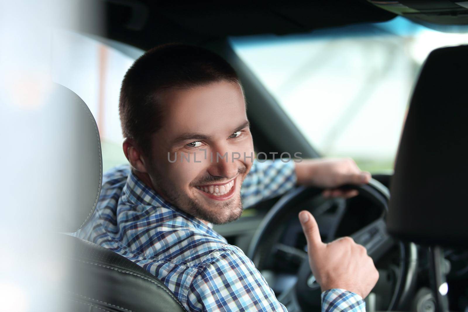 close up. modern man sitting in a car and showing his thumb up.