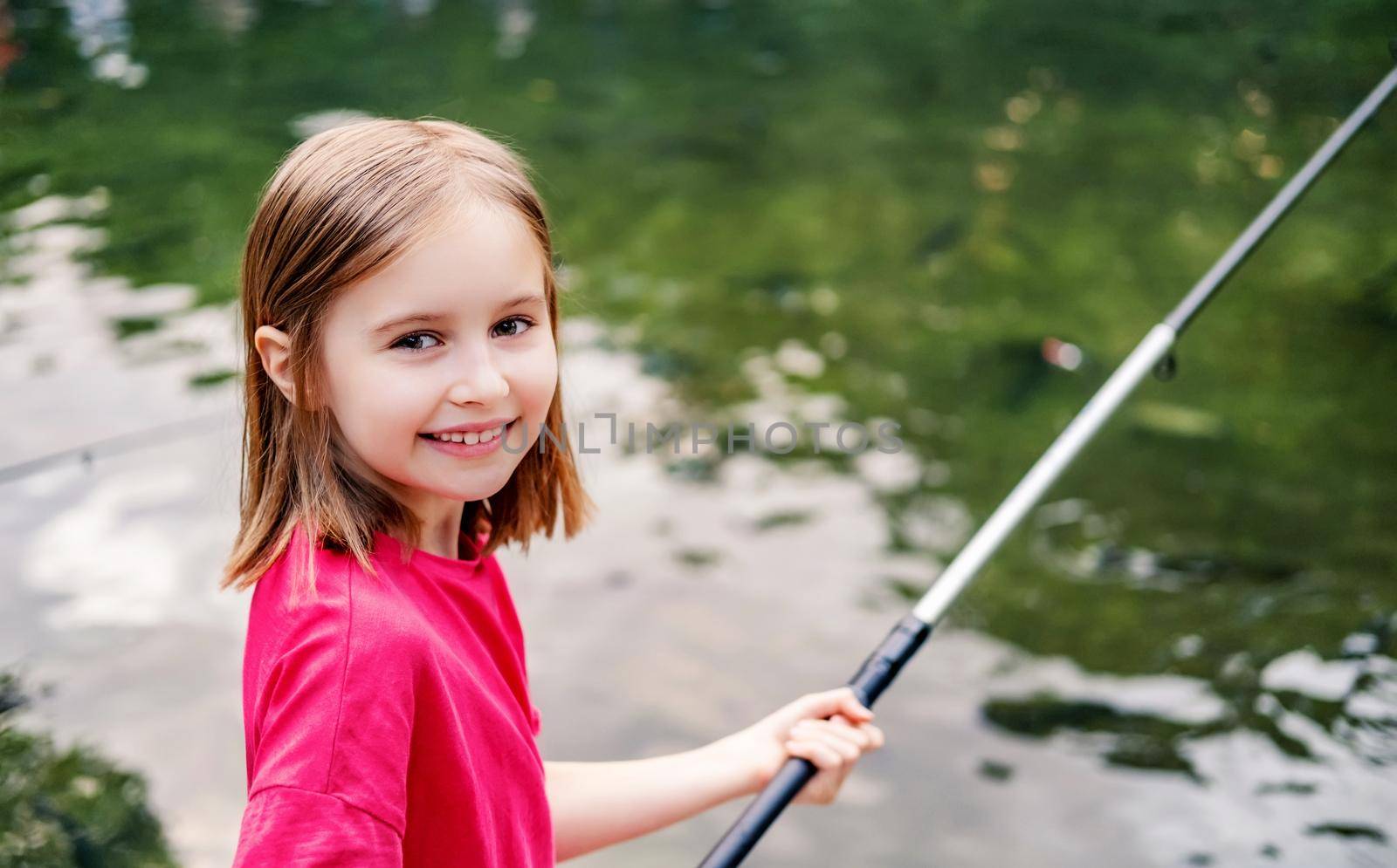 Little girl holding fishing rod on pond background