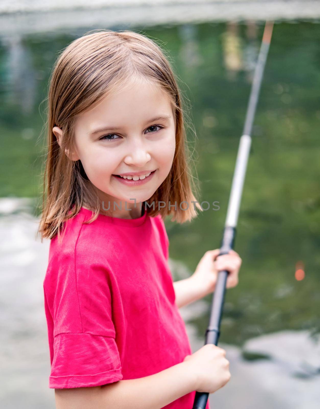 Little girl holding fishing rod on pond background
