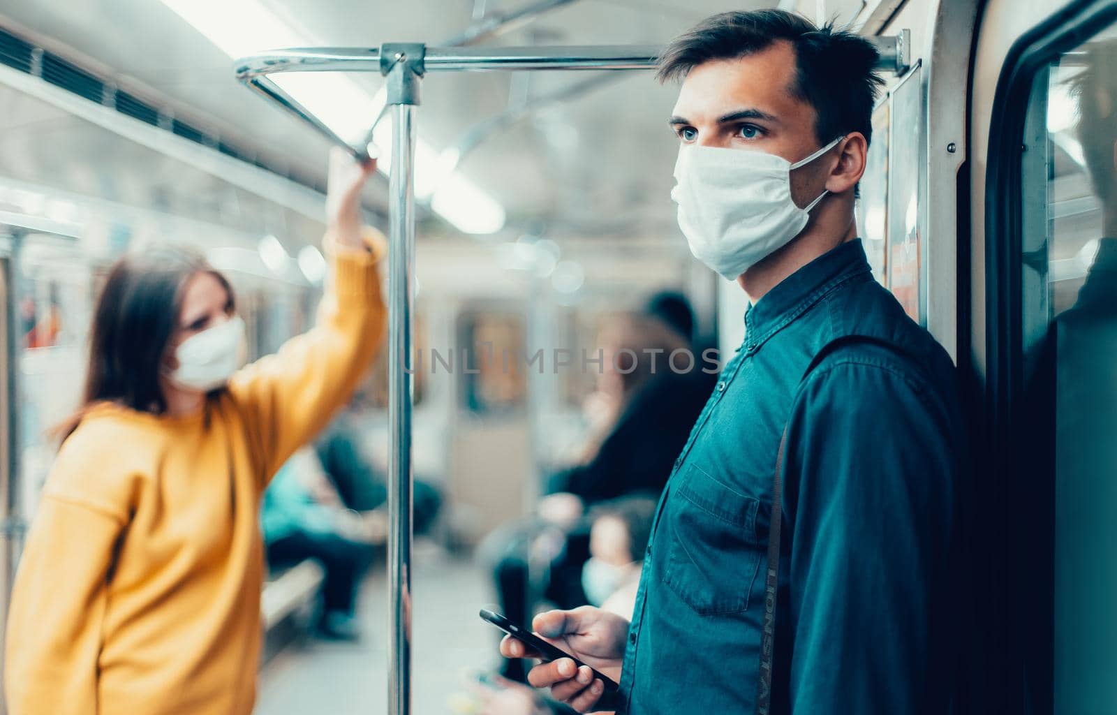 young man in a protective mask looking at the screen of his smartphone. coronavirus in the city