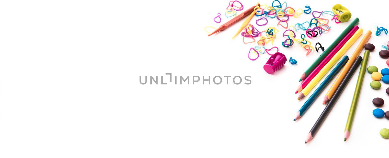 white backgrounnd with colourful kid 's sweets and stationery with copyspace. Childhood concept.