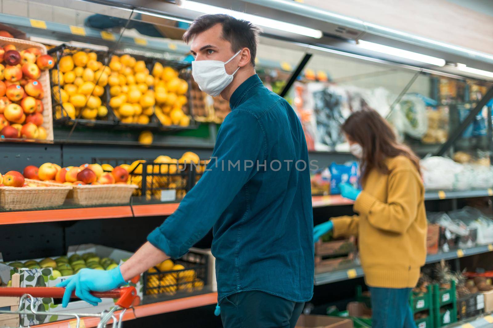 shoppers in protective masks choosing fruit in the supermarket . coronavirus in the city