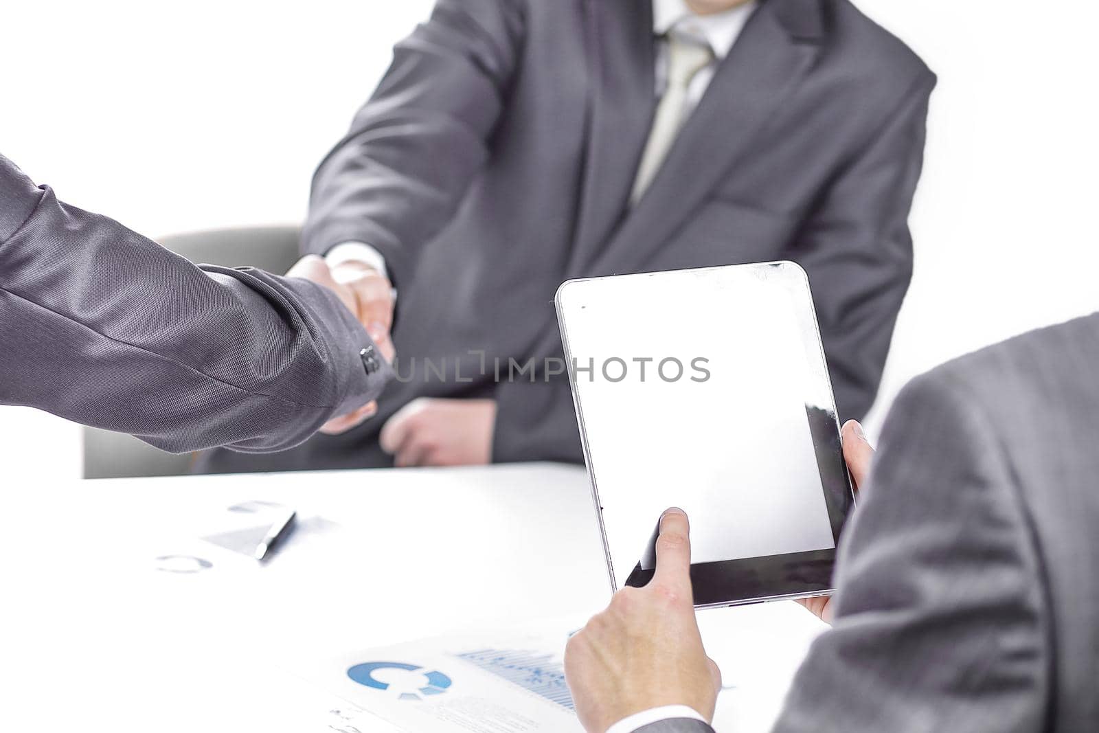 close up.businessman with a digital tablet on the background of a handshake of business partners