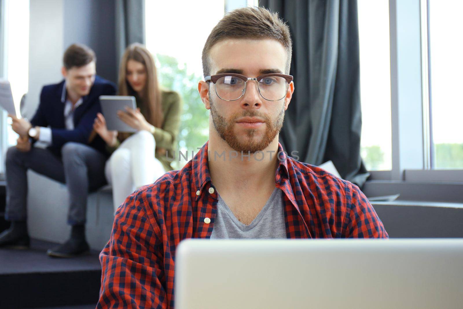 Young smart people are using gadgets while working hard in the modern office. Young man working on his laptop.