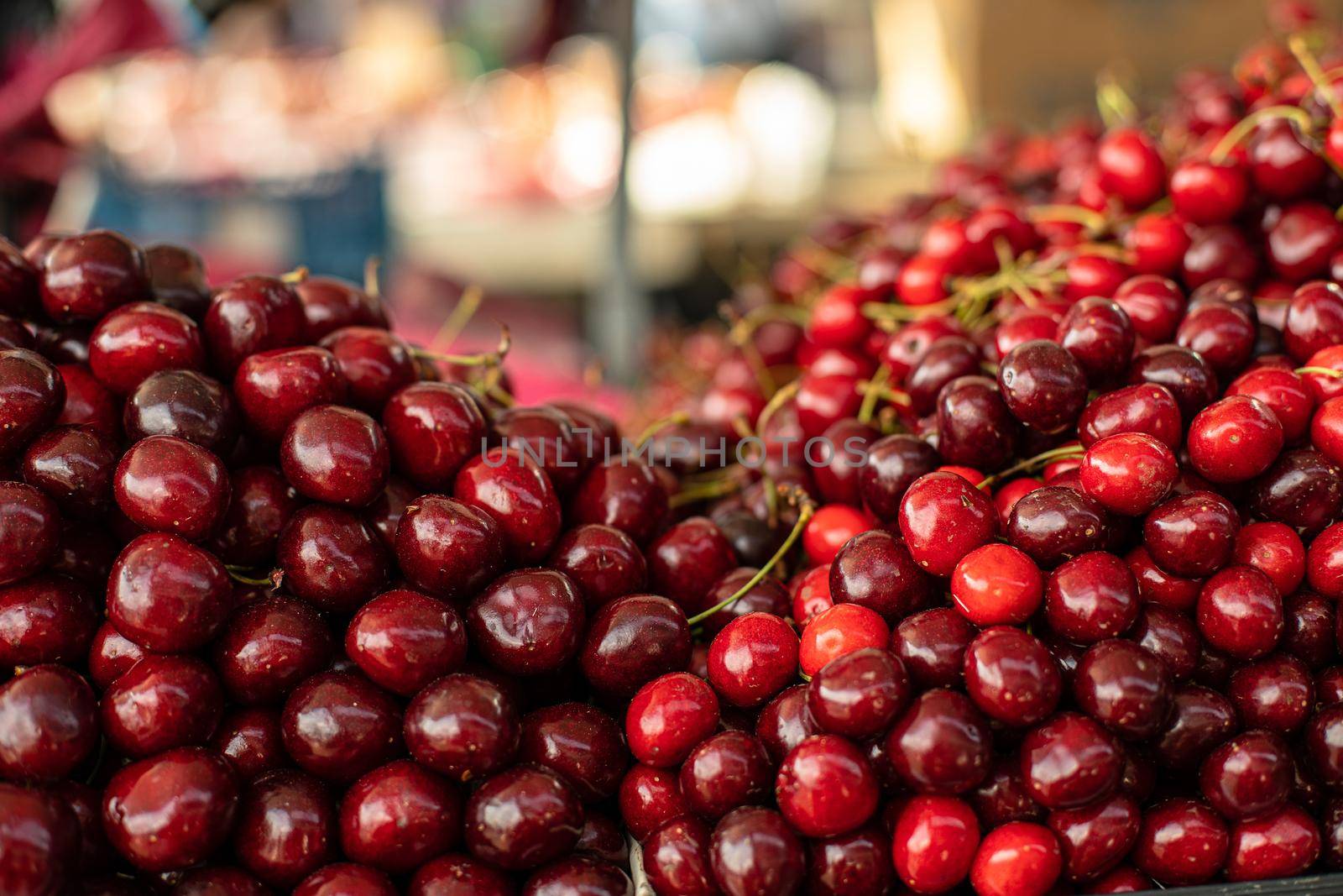 Closeup stock photo of heaps of fresh ripe sweet cherries for sale at the local wholesale market.