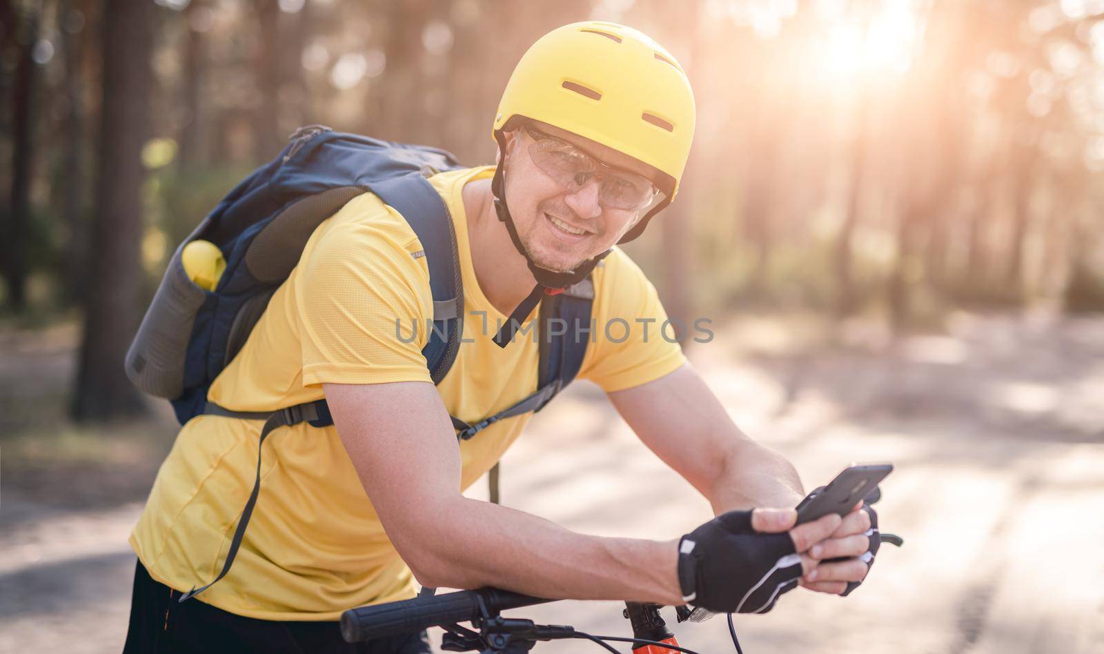 Bicyclist on bicycle checking gps navigator in smartphone in pine wood