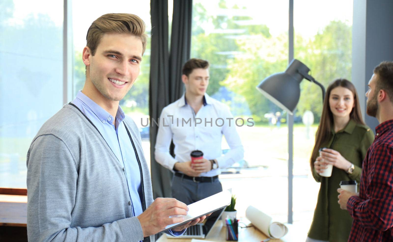 Smiling young man using digital tablet in the office.