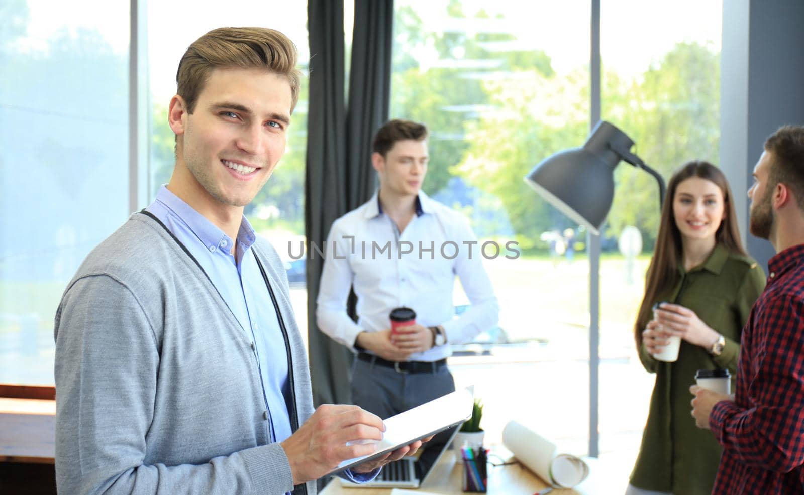 Smiling young man using digital tablet in the office. by tsyhun