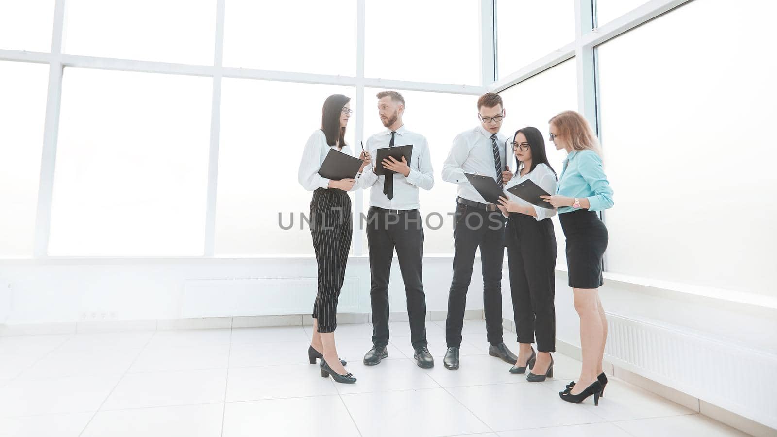 employees discuss business documents standing in the office lobby. photo with copy space