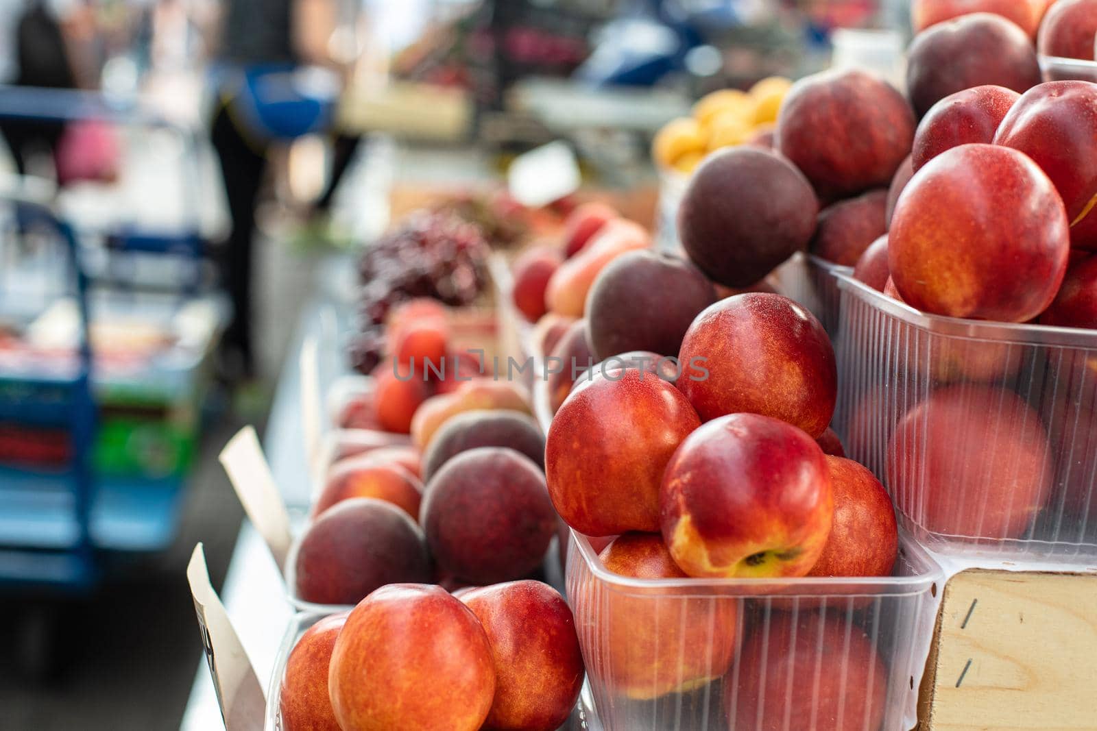 Picture of sweet, tasty and fresh peaches lying in small plastic boxes in the store.