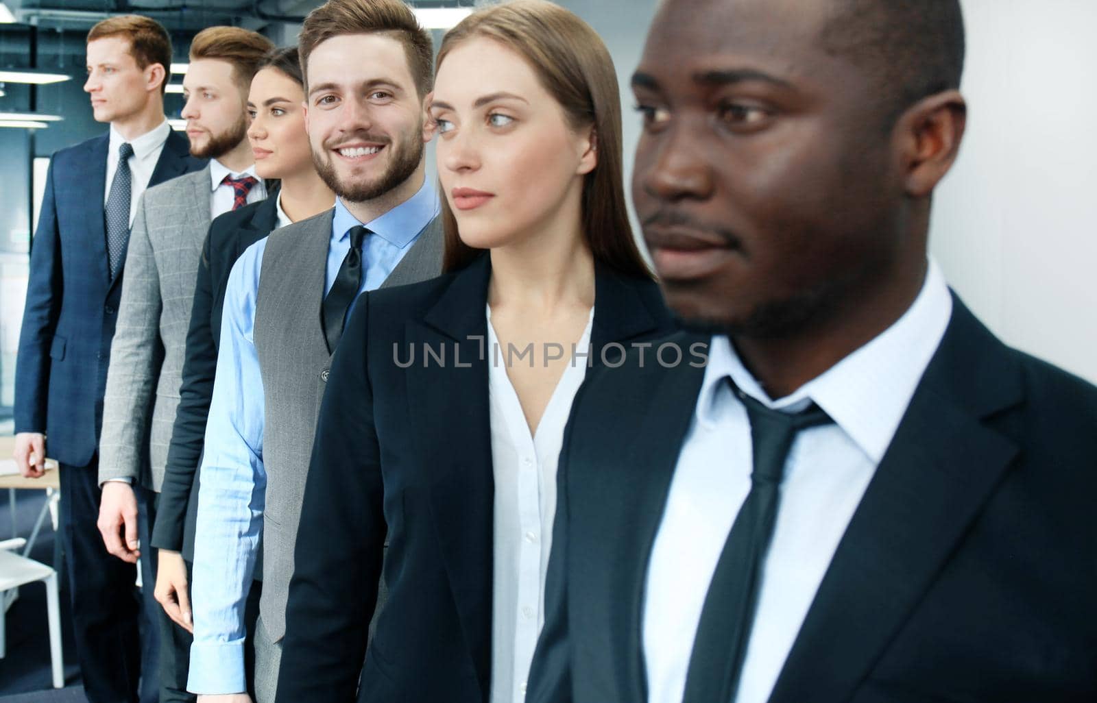 Happy smiling business team standing in a row at office.