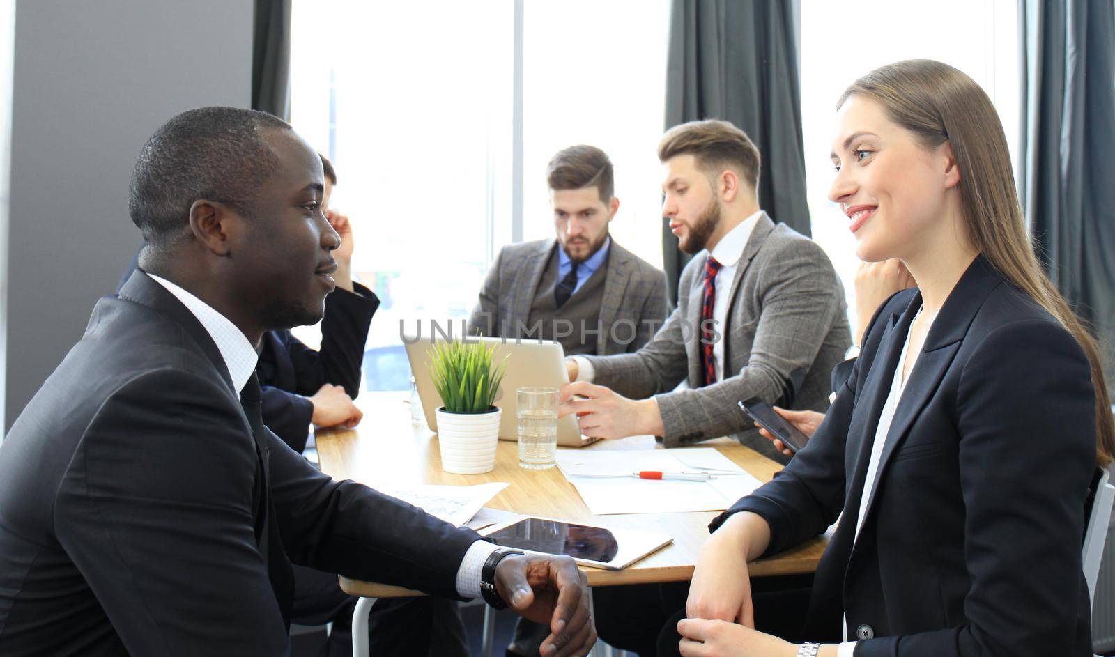 Image of two young business people interacting at meeting in office