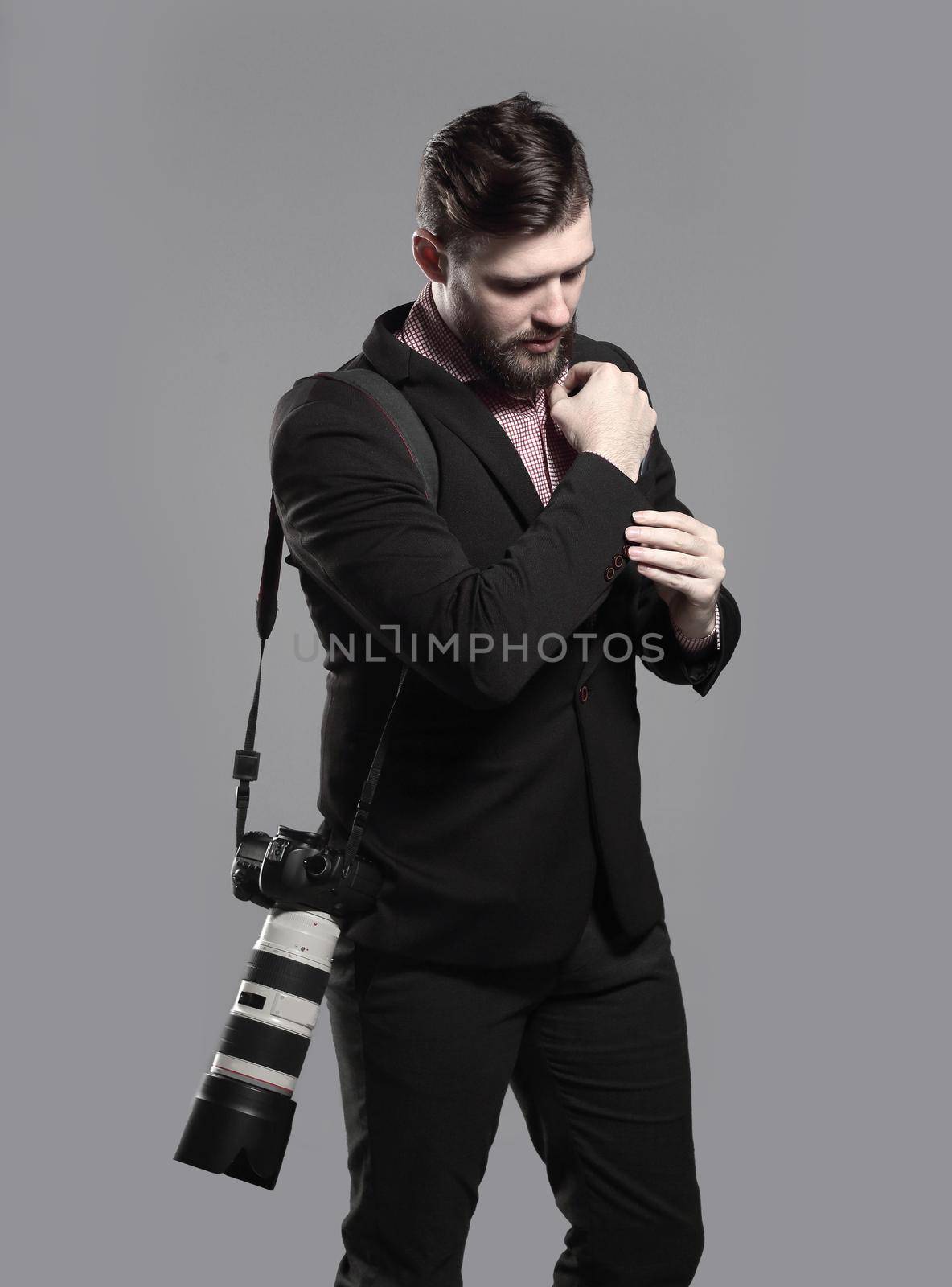professional photographer with camera, adjusting a cufflink.isolated on grey background.