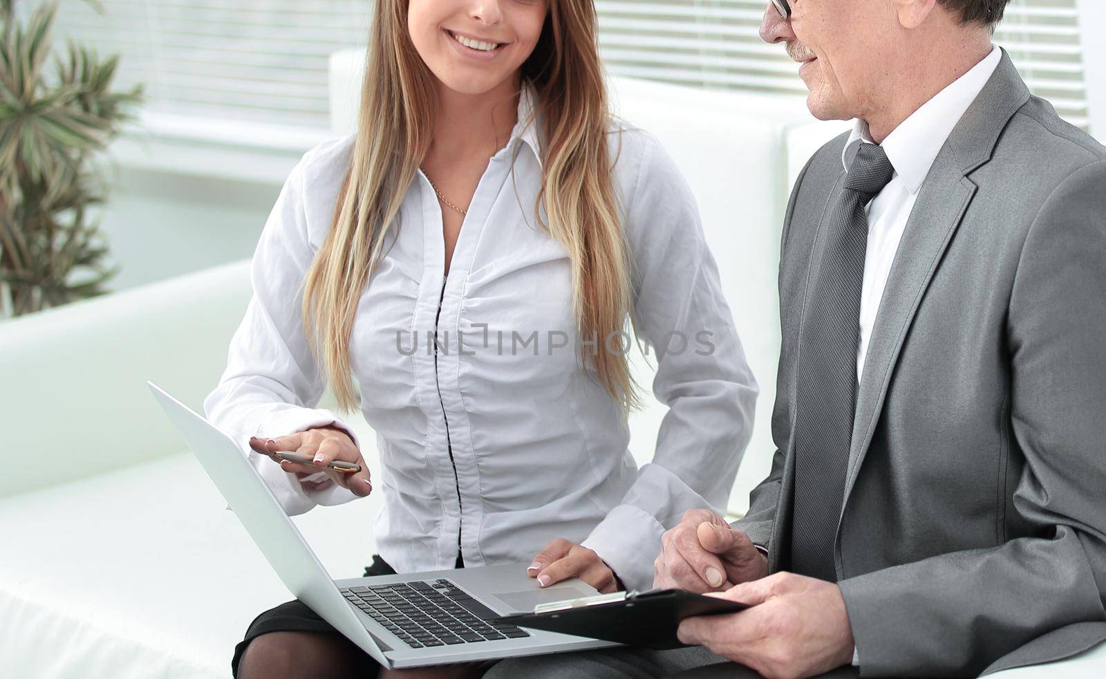 senior businessman and assistant using a laptop sitting in the lobby of the office.photo with place for text