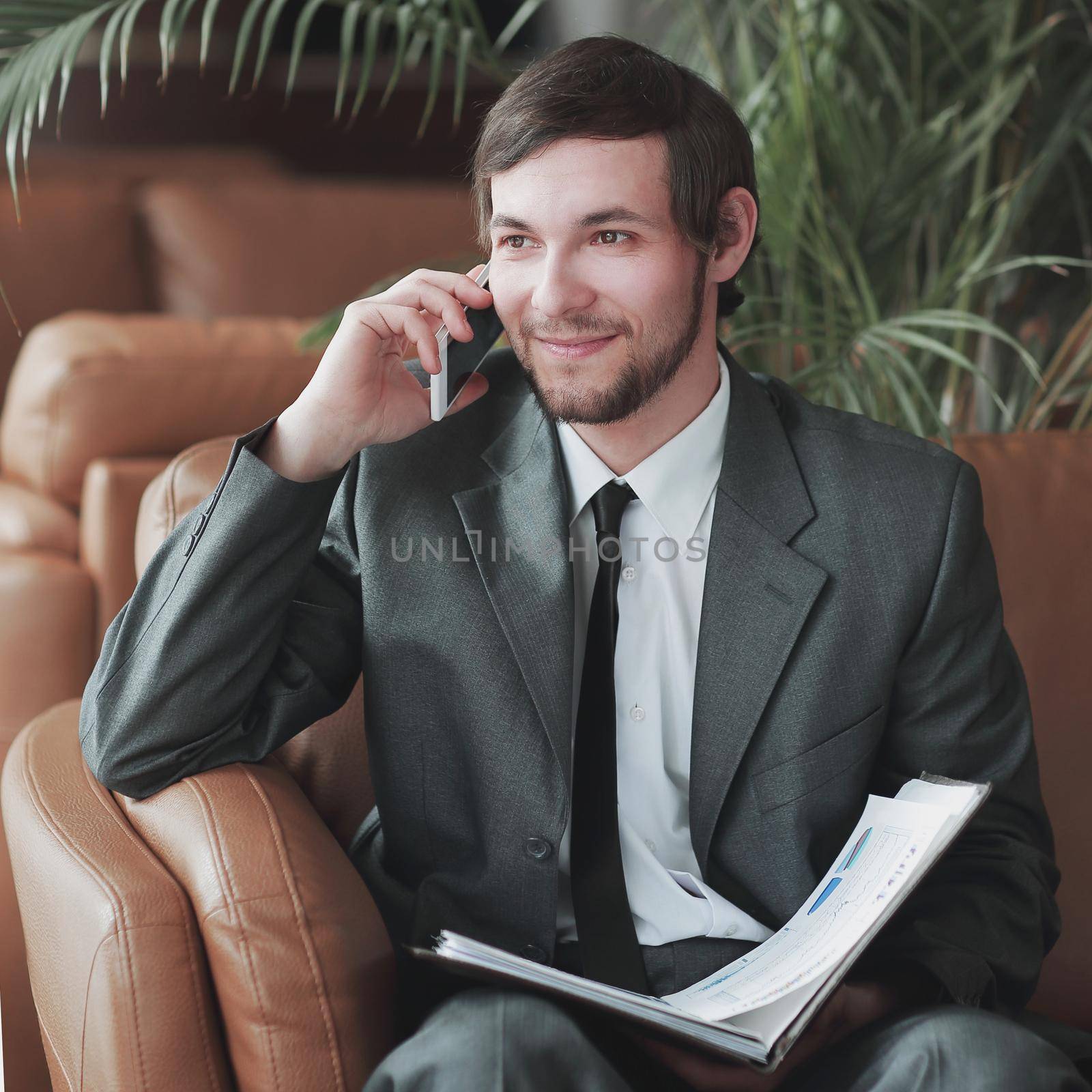 closeup. Businessman sitting in a business center reading documents while having a phone call