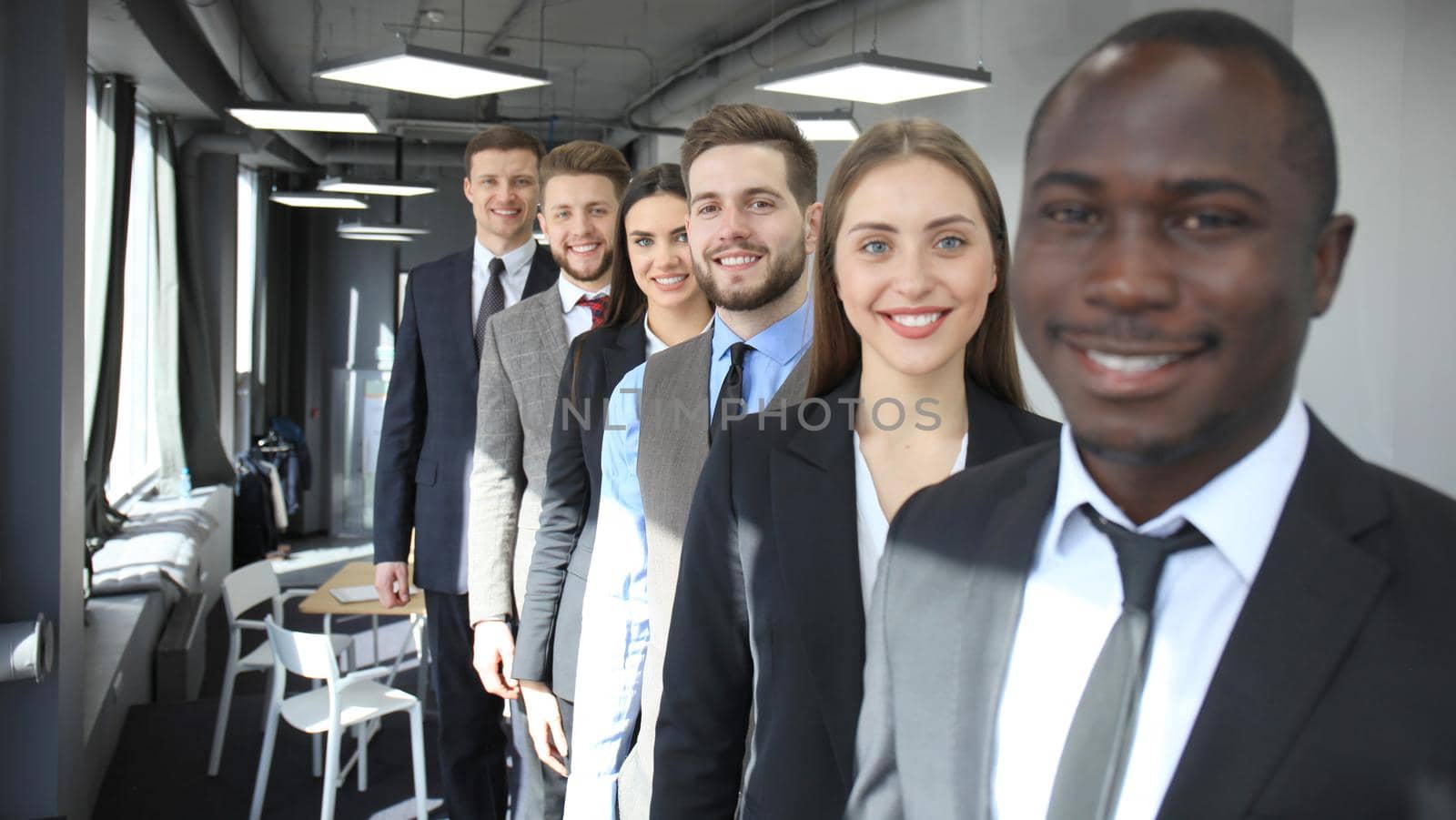 Happy smiling business team standing in a row at office.