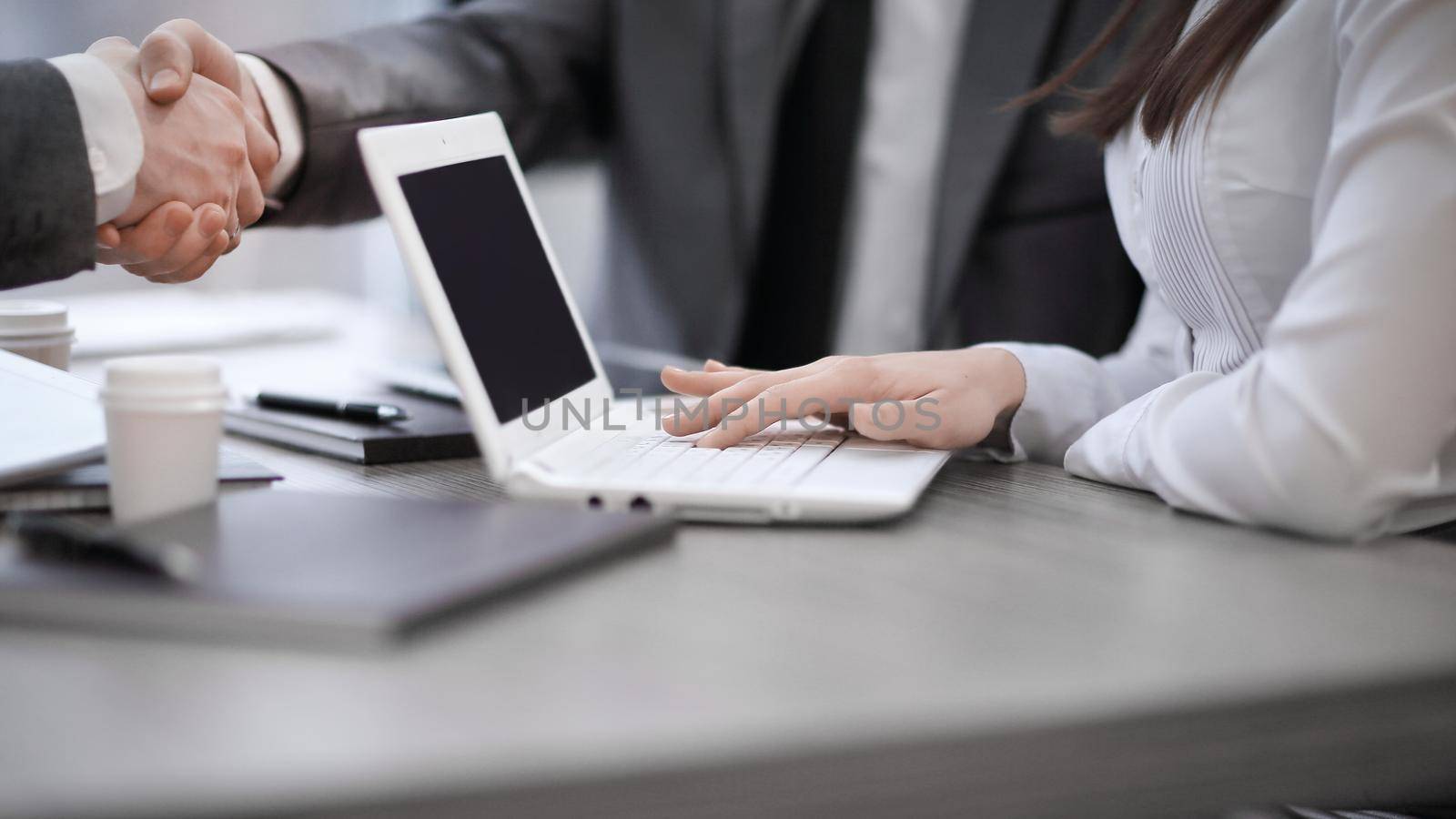Close up image of business partners handshake over office desk during meeting or negotiation.